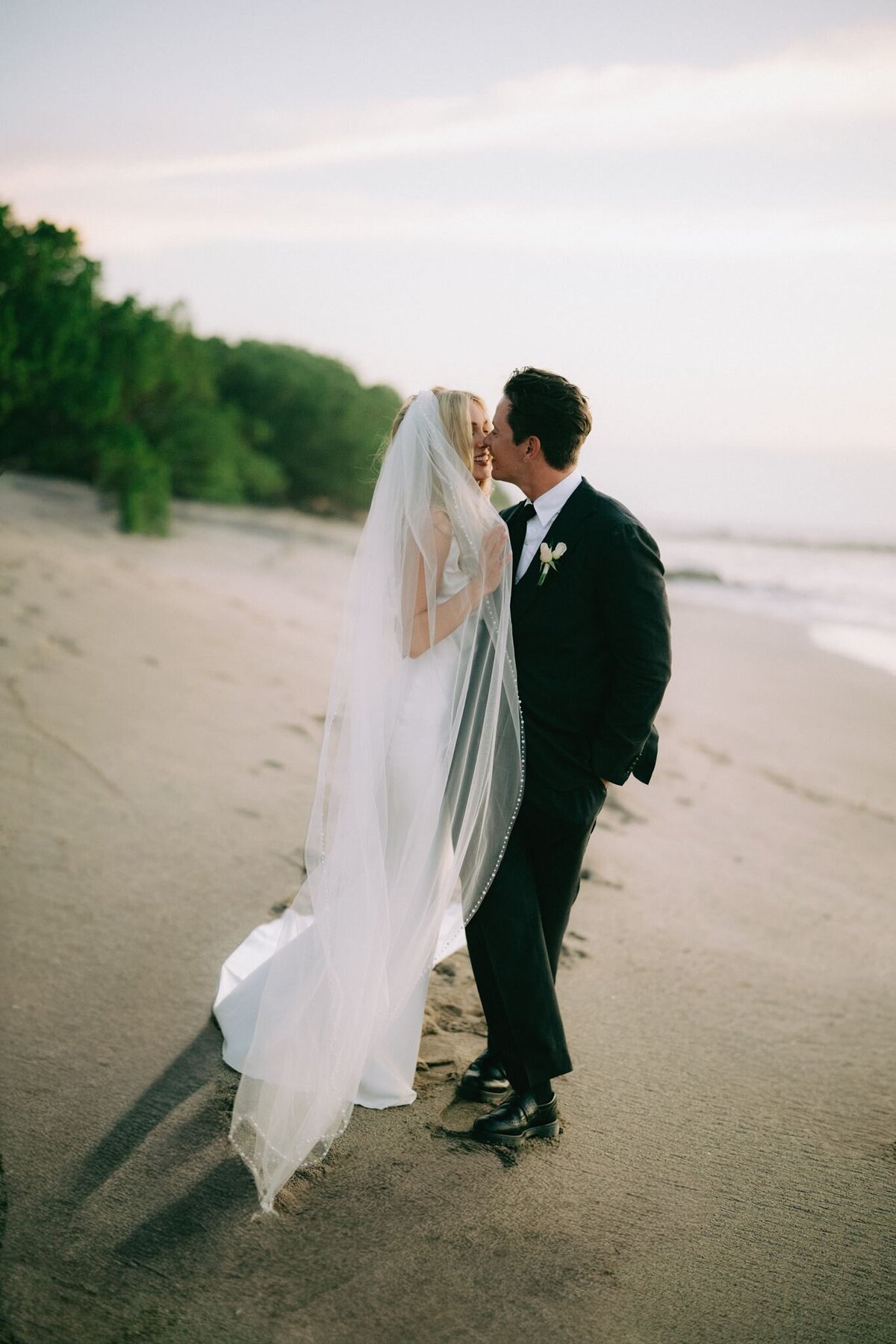 Newlyweds sharing a kiss by the coast