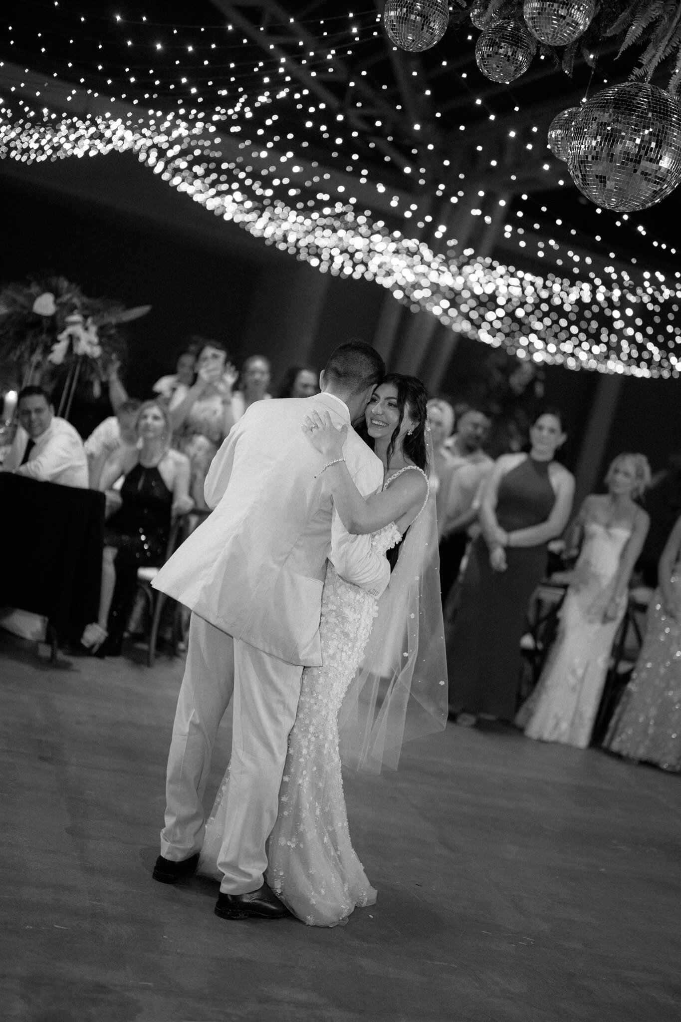 A wedding celebration beneath a canopy of lights, photographed in black and white