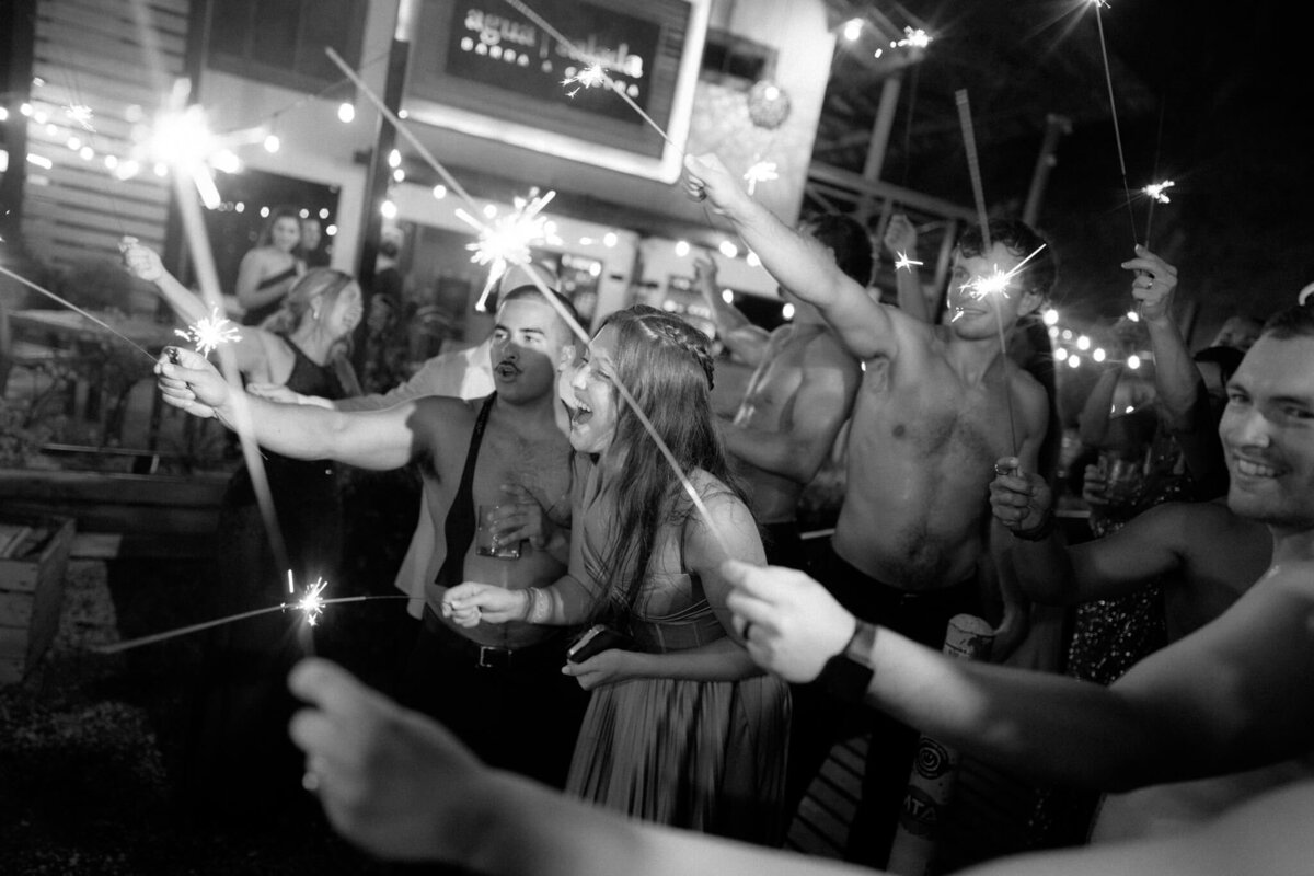 Wedding guests celebrating with sparklers at night, in black and white